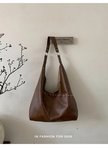 Detail der dunkelbraunen matten Ledertasche mit silbernen Metallösen und Nieten-Dekor