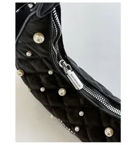 Detailed close-up of quilted black velvet fabric with white pearl accents and silver zipper