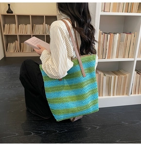 Détail du sac de plage tissé à rayures avec lanières en cuir marron dans une pièce