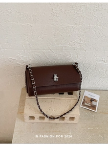 Detail of dark brown pebbled leather bag with silver chain strap and metal turn lock