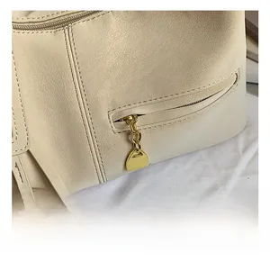 Détails de la quincaillerie dorée et grain de litchi sur le sac cabas en cuir beige