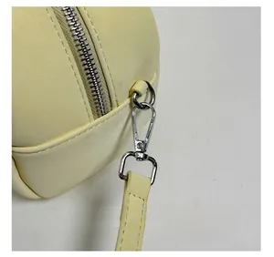 Close-up of silver metal swivel hook and zipper hardware on beige bowling handbag