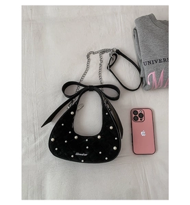 Detail view of black velvet crescent bag with white pearls, large bow and silver chain strap