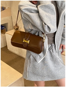 Detail view of the brown leather shoulder bag with a gold metal H-shaped buckle closure
