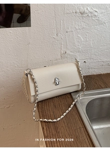 Close-up of off-white lychee leather flap bag featuring silver twist lock and rivet details