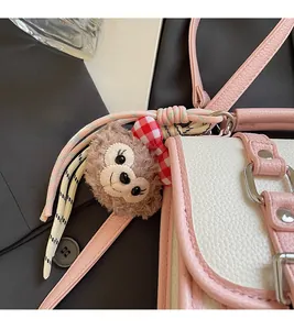Detail of pink and white pebbled leather bag with a plush bear charm and woven strap