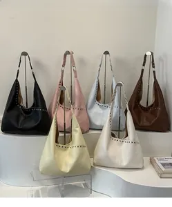 Große Shopper-Taschen mit Nieten in verschiedenen Farben auf minimalistischen Ständern