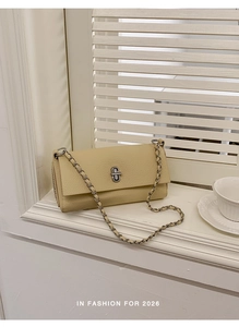 Detail of light yellow lychee pattern leather shoulder bag with silver turn-lock and chain