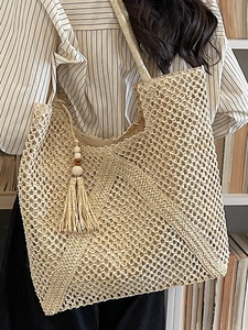 Handcrafted hollow weave straw tote bag with decorative tassels for beach and leisure