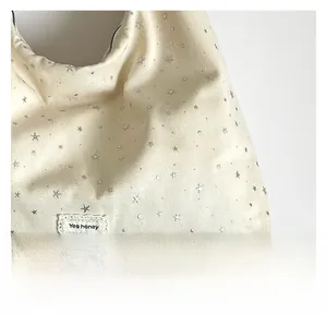 Detail of canvas tote bag featuring silver stars and lace-trimmed 'Yes honey' label