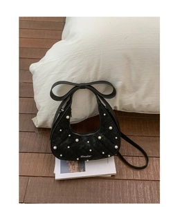Detail of black quilted hobo bag with pearl accents and an elegant bow handle