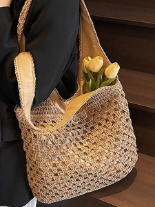 Straw woven tote bag for women with tulip decoration on a natural wooden background