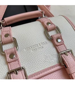 Close-up of pink and white lychee leather texture with silver buckle and embossed logo