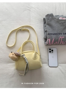 Detailed view of yellow bowling bag with plush bear charm and detachable shoulder strap