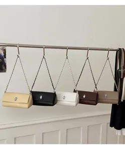 Five lychee pattern crossbody bags in neutral tones with metallic chain straps and turn-locks