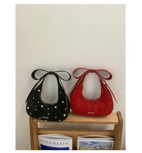 Detail of crescent bags with bow handles in black pearl and red quilted suede finishes