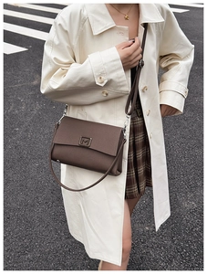 Close-up of coffee brown leather shoulder bag featuring metallic M logo and matte finish