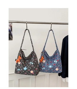 Dettaglio di grandi borse tote in tela grigia e blu denim con applicazioni floreali