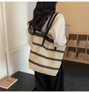 Détail d'un grand sac cabas tissé rayé avec des anses en cuir noir de haute qualité