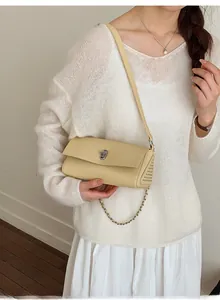Close-up of cream yellow lychee leather bag with silver lock and metal rivet detail