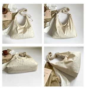 Detail of beige canvas tote with star print and pleated scrunchie shoulder strap