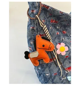 Dettaglio del ciondolo a forma di cavallo in pelle arancione su borsa in denim