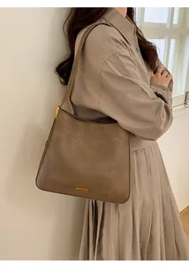 Gros plan d'un sac hobo en cuir plissé taupe avec un logo doré élégant et texture riche
