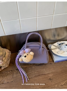 Detail of purple bowling bag featuring a plush bear charm and woven tassel accent