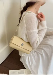 Close-up of cream yellow crossbody bag showing litchi grain leather and metal clasp