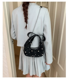 Detailed view of black quilted moon bag with bow handle and pearl embellishments