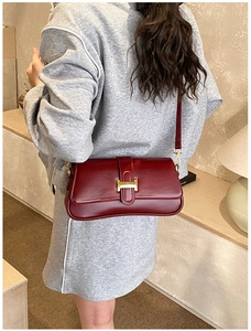 Detail view of burgundy shoulder bag with iconic golden H clasp on smooth leather