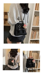 Close-up of black litchi pattern leather bag with vintage buckles and bear charm