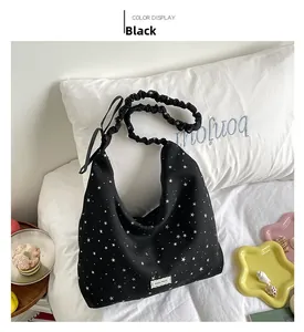 Detail of black polka dot canvas tote bag with stylish ruffled shoulder strap on bed
