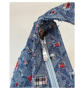 Dettaglio macro della cerniera in metallo argentato sulla borsa tote in denim azzurro