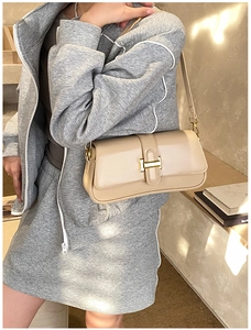 Detailed close-up of beige leather shoulder bag with golden U-shaped buckle for women