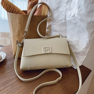 French retro cream fabric crossbody bag with metal M logo on dark wood table