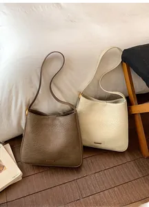 Détail du cuir texturé vintage et ferrures dorées sur des sacs seaux minimalistes