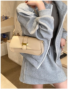 Close-up of cream leather shoulder bag featuring a gold H-shaped clasp for luxury detail