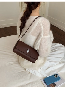 Detail of dark brown lychee leather bag with silver twist lock and metal chain strap