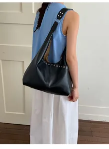 Detail der schwarzen Shopper Tasche mit silbernen Metallösen und breitem Schultergurt