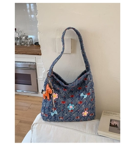 Dettaglio borsa hobo in denim blu con motivo a quadri rossi e fiori applicati 3D