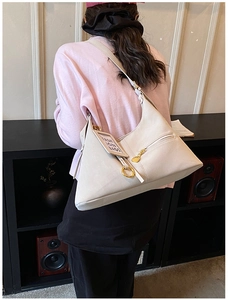Détail du sac hobo crème avec ferrures dorées et étiquette décorative de mode