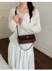 Detail of dark brown lychee textured leather crossbody bag with silver rotating lock