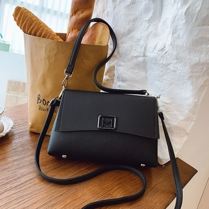 Close-up of black crossbody bag with M logo, textured leather, and silver studs