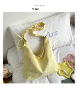 Detail of yellow canvas hobo bag featuring silver star prints and ribbon shoulder strap