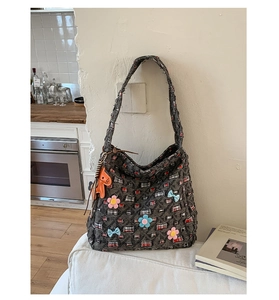 Dettaglio della grande borsa tote in tweed con fiori 3D e ciondolo a forma di cavallo arancione