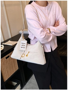 Détail d'un sac hobo blanc en forme de croissant avec un porte-cartes décoratif et un zip