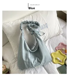 Detail of light blue hobo bag with silver stars and ruffled strap on white pillow