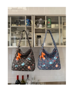 Dettaglio della borsa tote in tweed con fiori 3D, fiocco blu e ciondolo a cavallo arancione