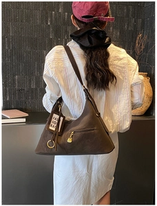 Détail du sac cabas marron foncé avec fermeture éclair dorée et étiquette de mode